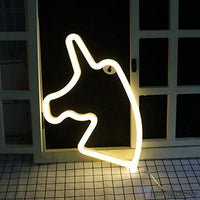 Néon LED licorne blanc chaud en silhouette de profil posé au sol, lumière douce devant une porte