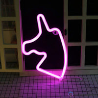 Néon LED licorne rose vif posé sur le sol devant une porte vitrée, lumière rose intense décoration chambre