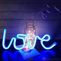 Néon LED love bleu posé sur un bureau à côté d'un vase fleuri, décoration chambre romantique