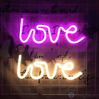 Deux néons LED love en violet et blanc chaud accrochés côte à côte sur un mur carrelé décoré