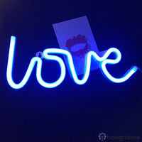 Néon LED love bleu électrique en script accroché au mur dans une pièce sombre, décoration chambre