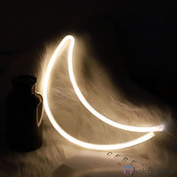 Néon LED lune croissant blanc chaud posé sur fourrure blanche avec bouteille déco, ambiance nuit douce