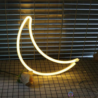 Néon LED lune croissant blanc chaud posé sur sol carrelage avec fleurs, décoration chambre minimaliste