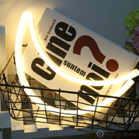 Néon LED lune croissant blanc chaud posé dans panier fil avec magazines, décoration bureau cosy