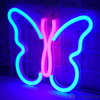 Néon LED papillon bleu turquoise et rose vif bicolore accroché sur mur carrelé dans l'obscurité, déco chambre